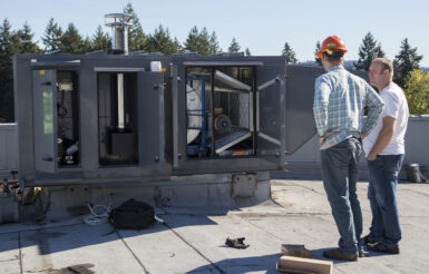 Two people working and discussing a rooftop unit