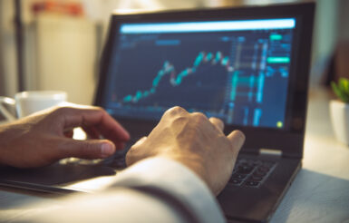 person typing on laptop with benchmarking data on screen